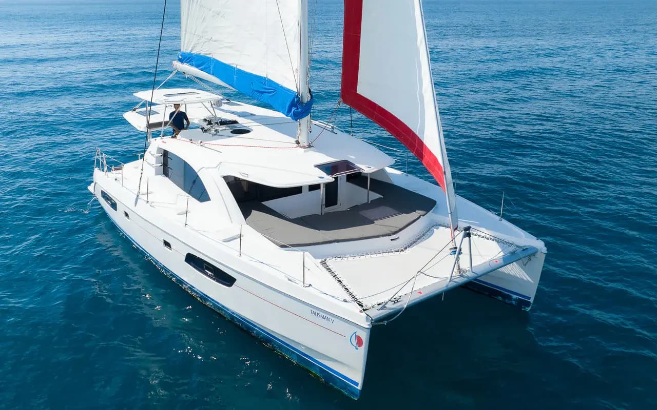 Aerial view of a sailing catamaran with sails raised gliding across deep blue water off the Riviera Maya