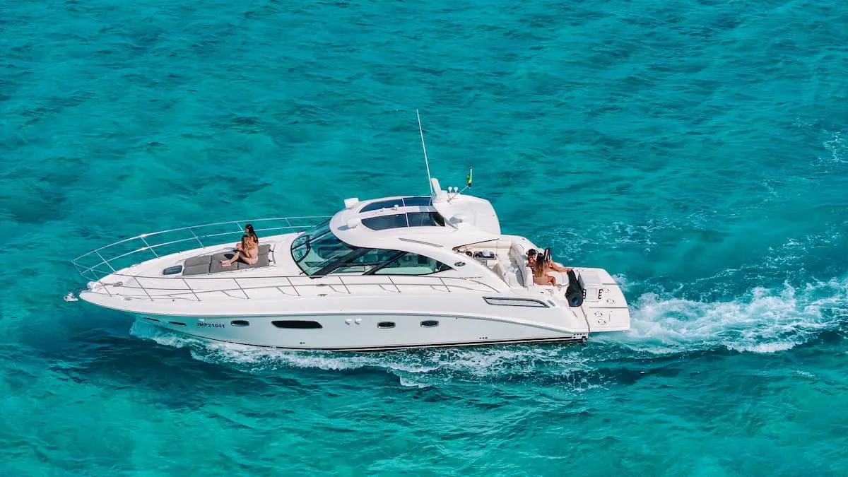Yacht cruising through turquoise water off Bayahibe with a guest lounging on the bow
