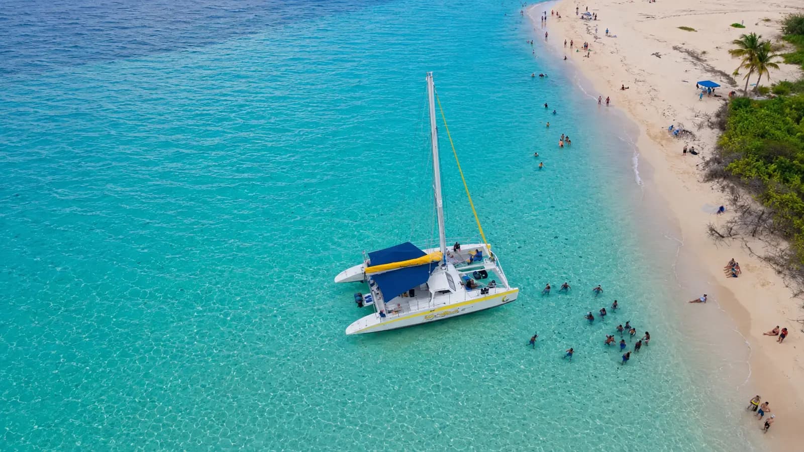 Sailing catamaran by a white-sand beach with swimmers near Fajardo, Puerto Rico