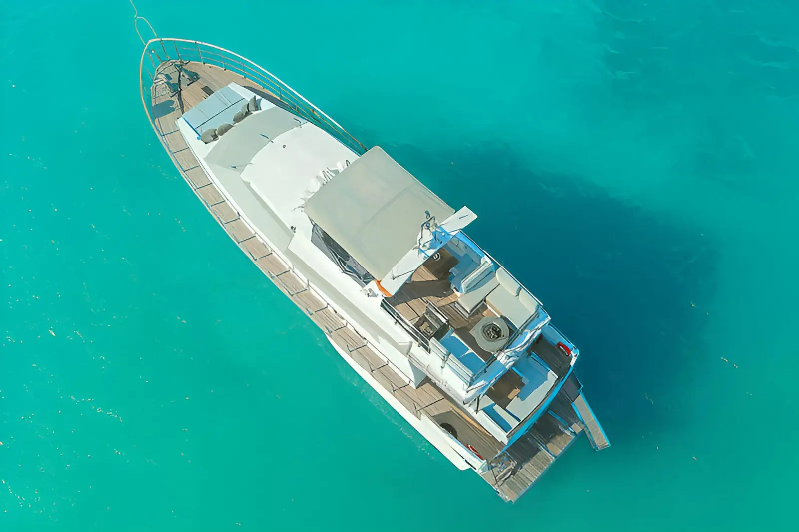 Top-down aerial view of a large motor yacht anchored in turquoise water off Mykonos