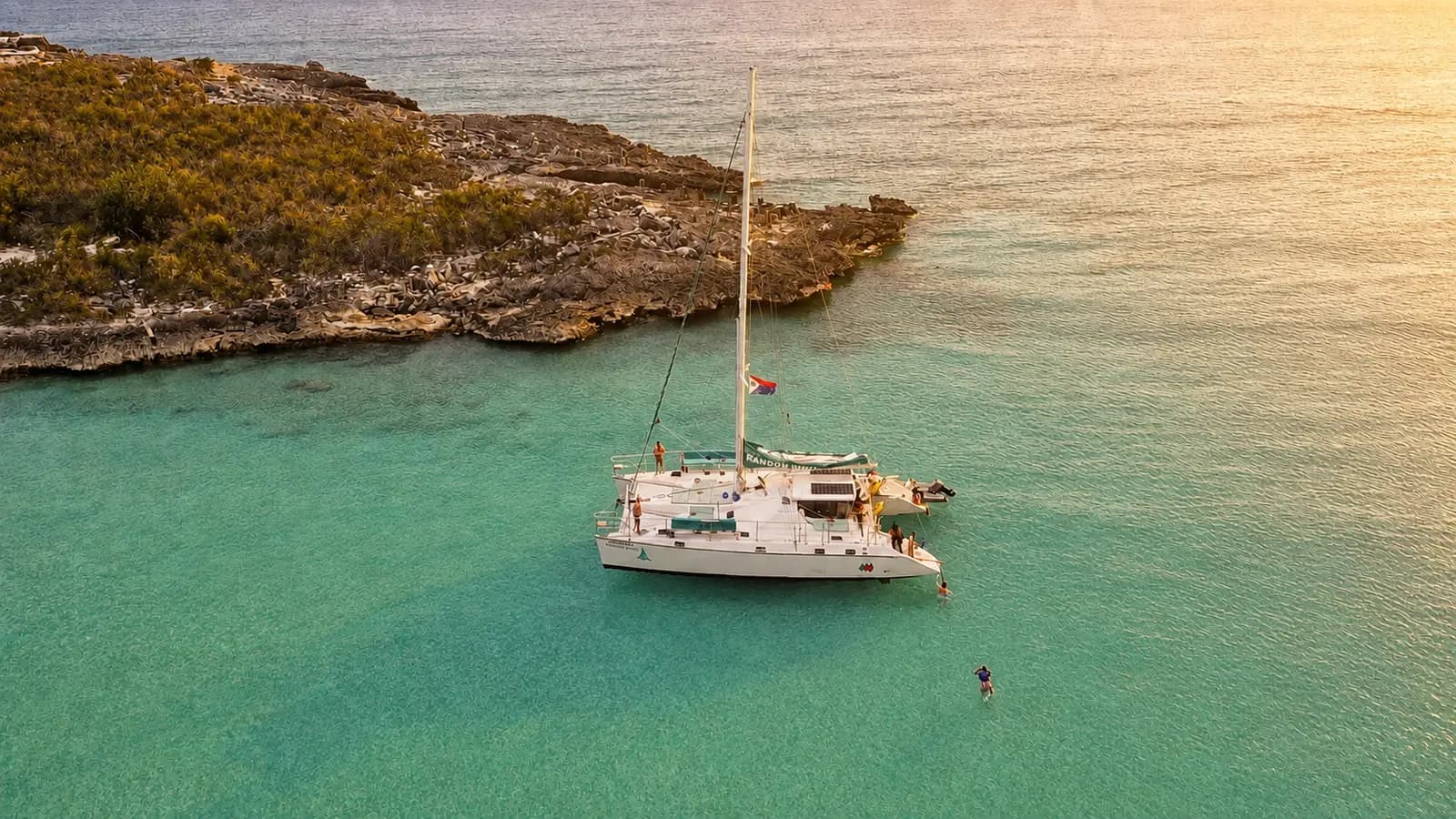 Sailing catamaran anchored off a rocky point in St. Maarten