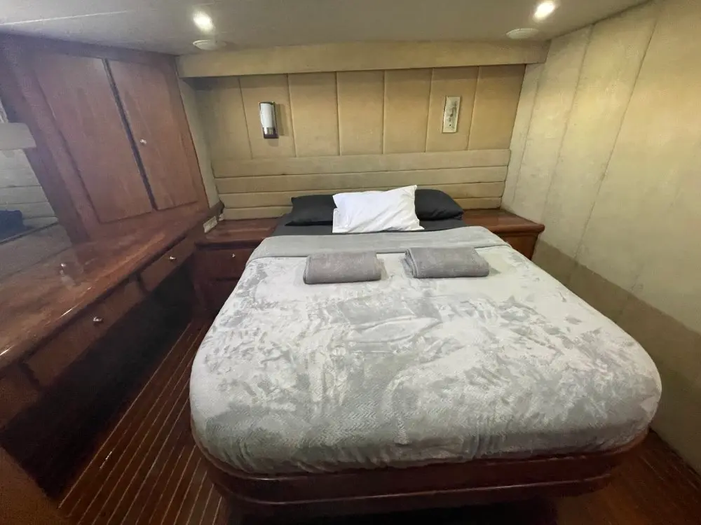 Yacht guest cabin with a gray-covered double bed, wall lamps and polished wood floors