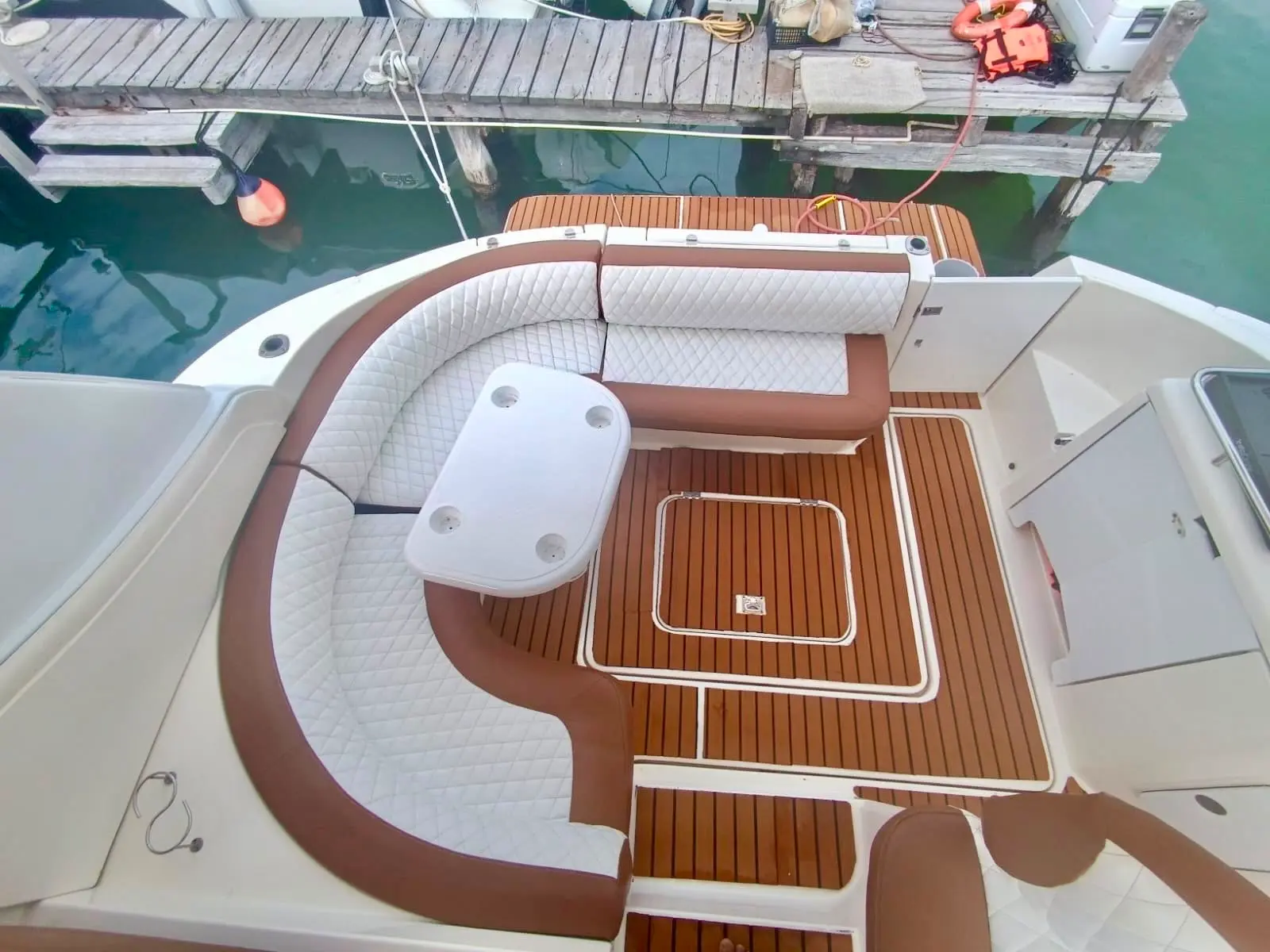 Looking down into an express cruiser's cockpit with quilted U-shaped seating and teak floor at a dock