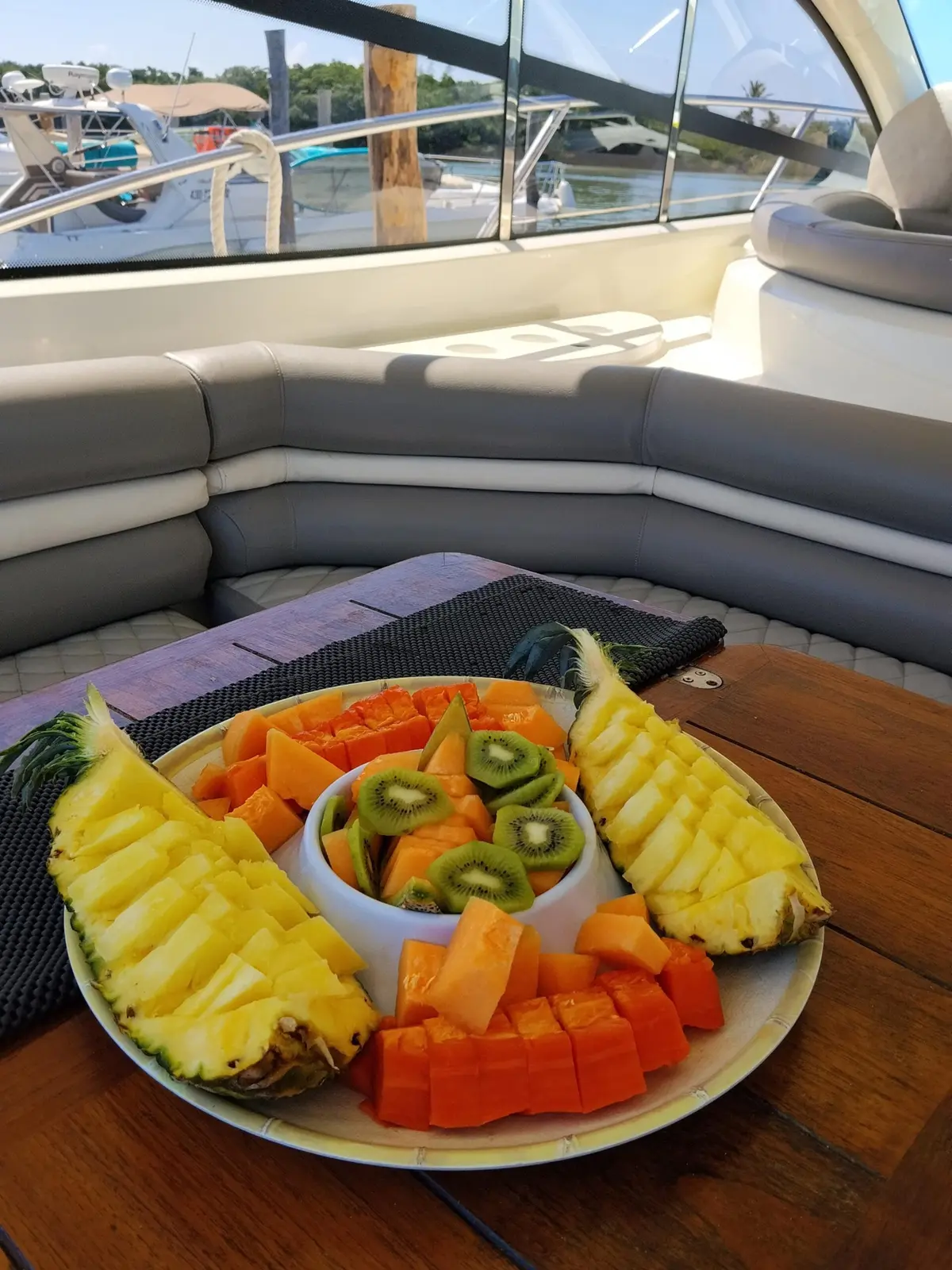 Platter of sliced pineapple, papaya and kiwi on the cockpit table of a yacht