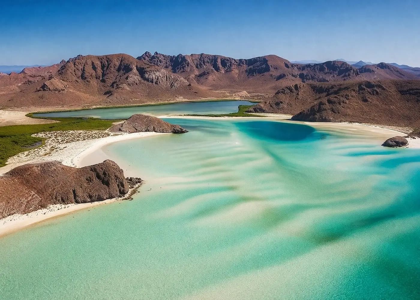Aerial view of Balandra Bay's shallow turquoise water, rippled white sandbars and desert mountains