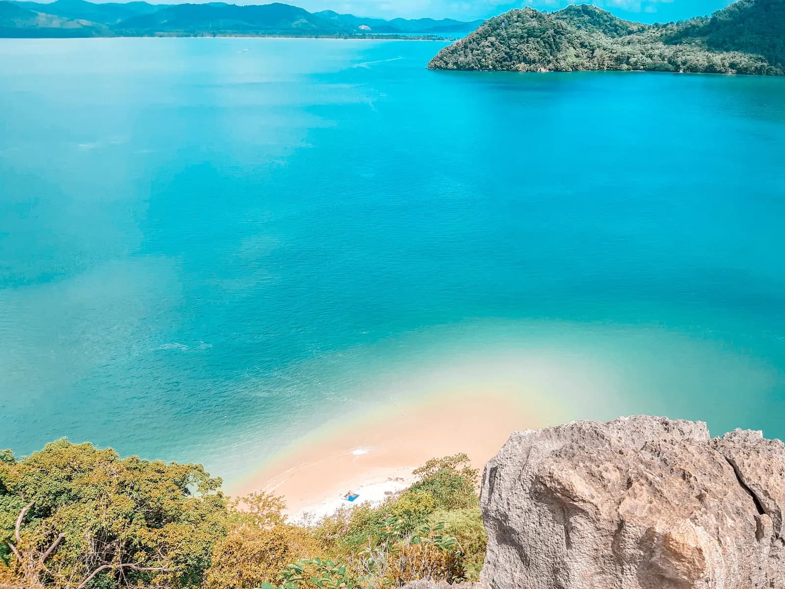 Turquoise bay and a curving white sandbar seen from a clifftop viewpoint on Hong Island
