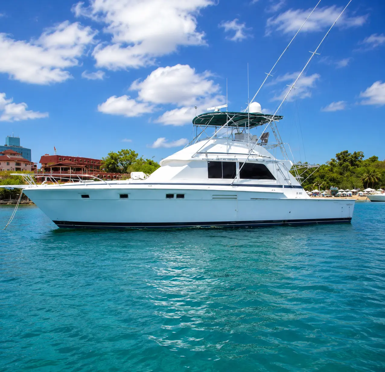 Sportfishing boat with flybridge and outriggers anchored in turquoise water off the Puerto Plata coast