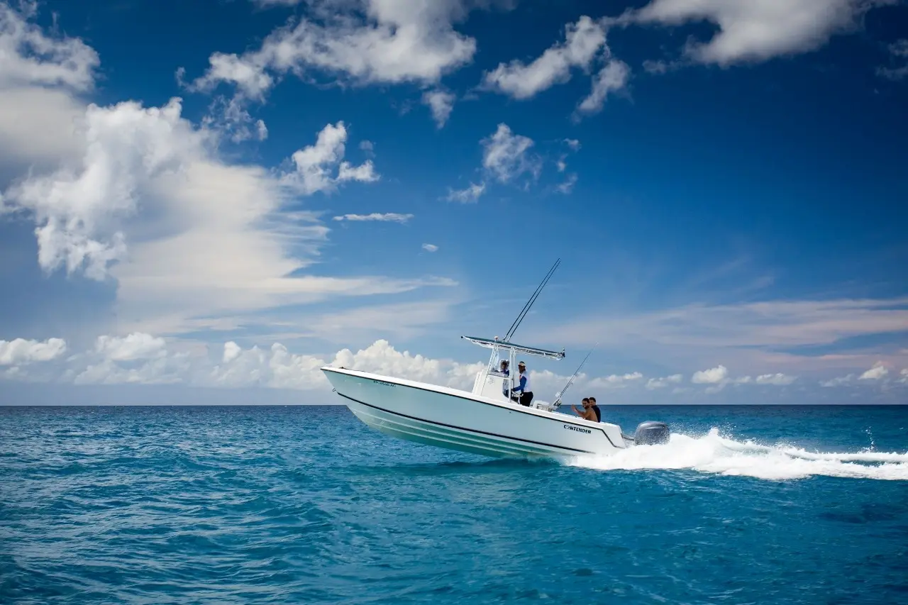 Speedboat throwing a white wake as it races across the open sea under big clouds