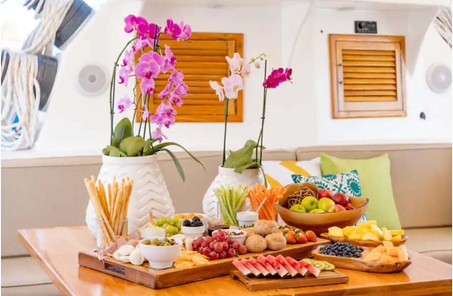 Grazing table with orchids, breadsticks, grapes, watermelon and cheese in the catamaran lounge