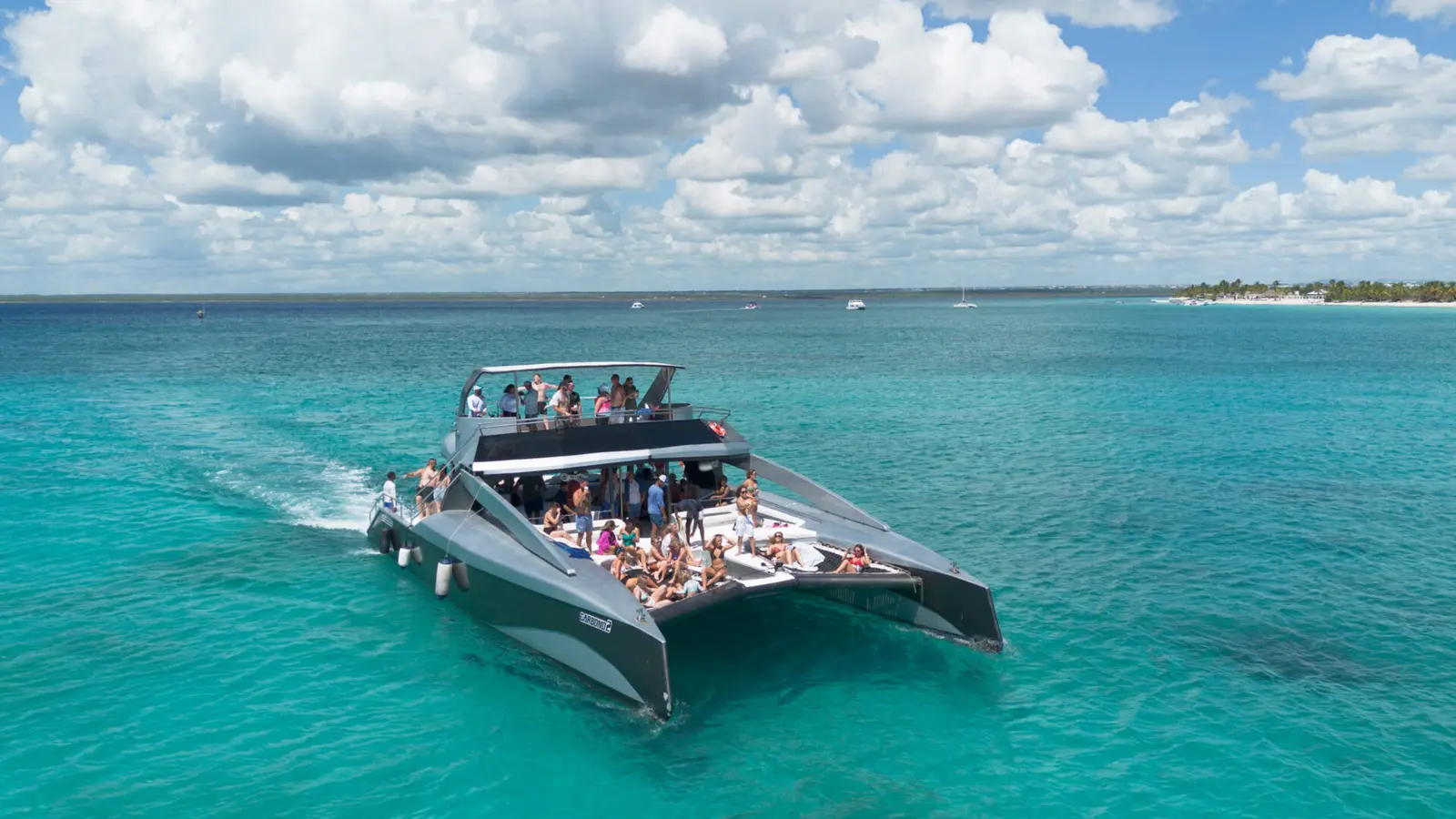 Aerial view of a power catamaran packed with guests cruising turquoise water off Punta Cana