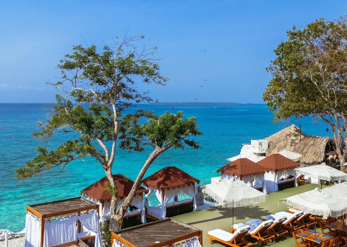 Curtained cabanas and sun loungers overlooking turquoise sea at an island beach club in the Rosario Islands