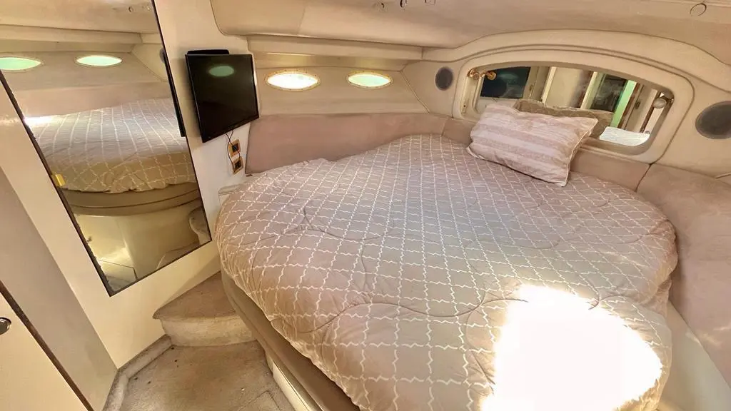 Yacht cabin with a quilted double bed, wall-mounted TV and a mirrored wall