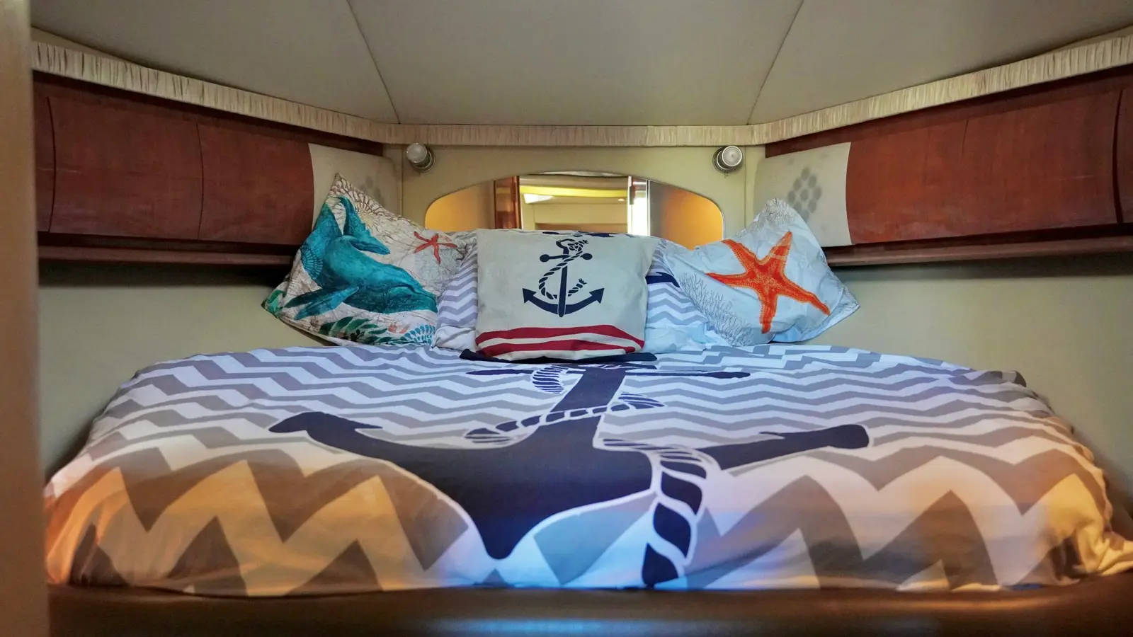 Cabin berth with chevron bedding, an anchor print and nautical throw pillows on a yacht