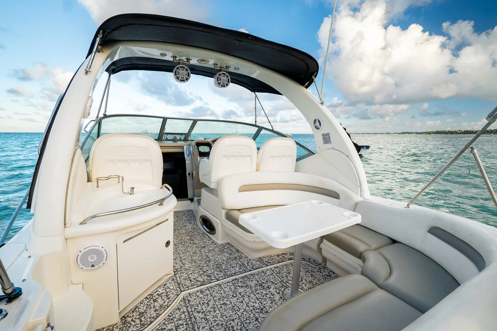 View forward over the yacht's twin helm seats and fold-out table to the windshield, sea on both sides