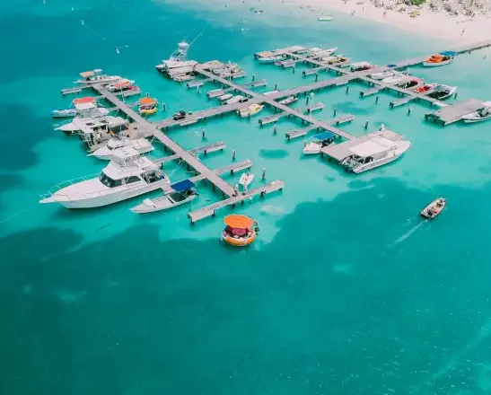 Aerial view of yachts and motorboats moored along wooden piers in turquoise water off Aruba