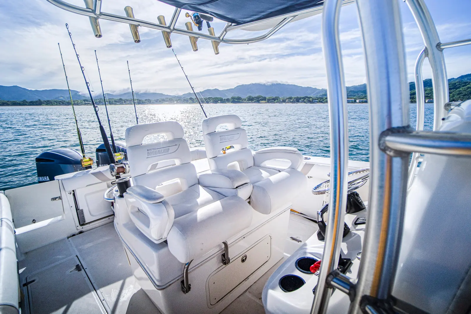 Twin white helm seats under the T-top of a center console boat, rods standing ready by the Papagayo coast