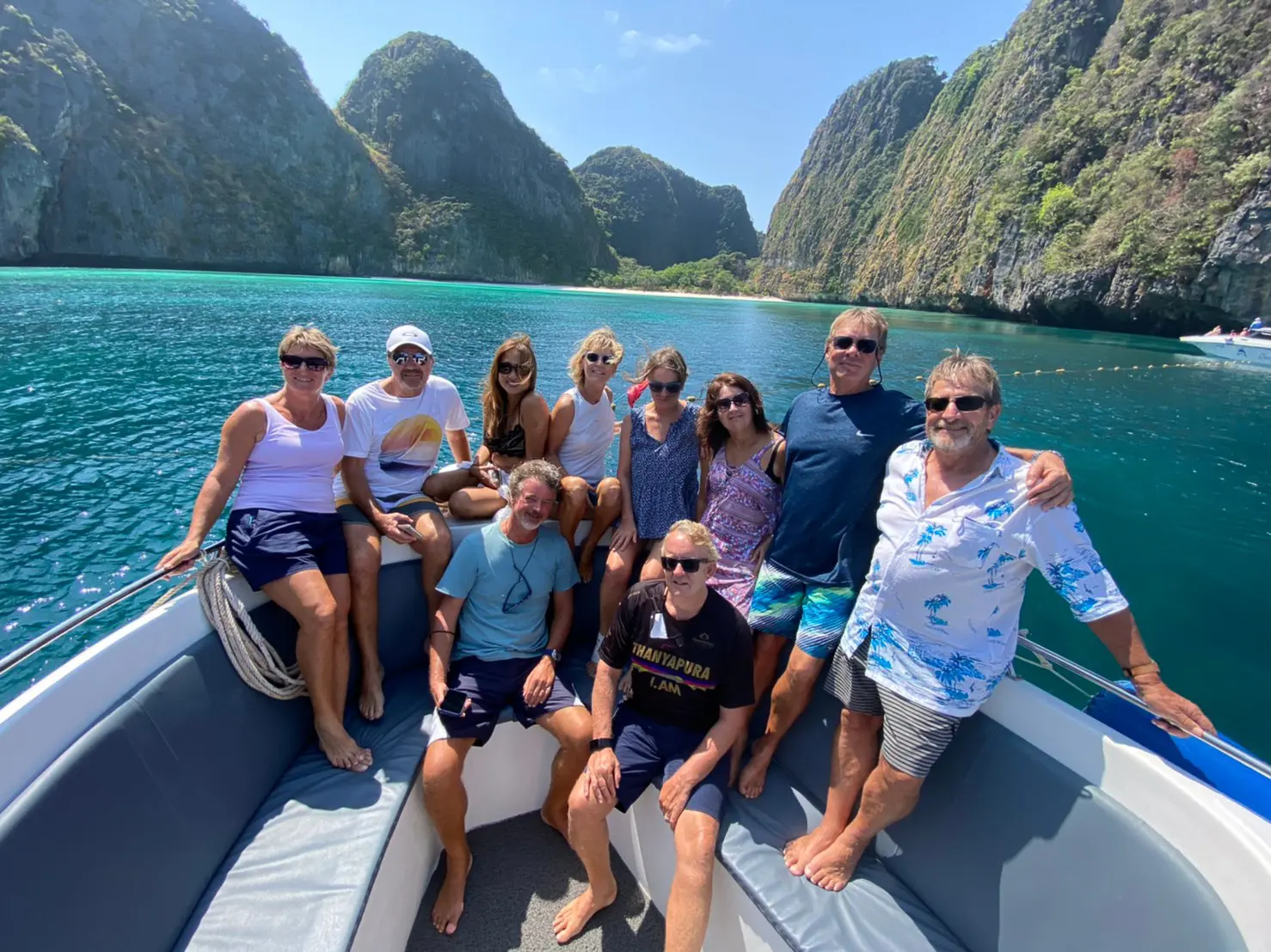 Group of guests posing on the speedboat bow among the limestone cliffs of Phi Phi