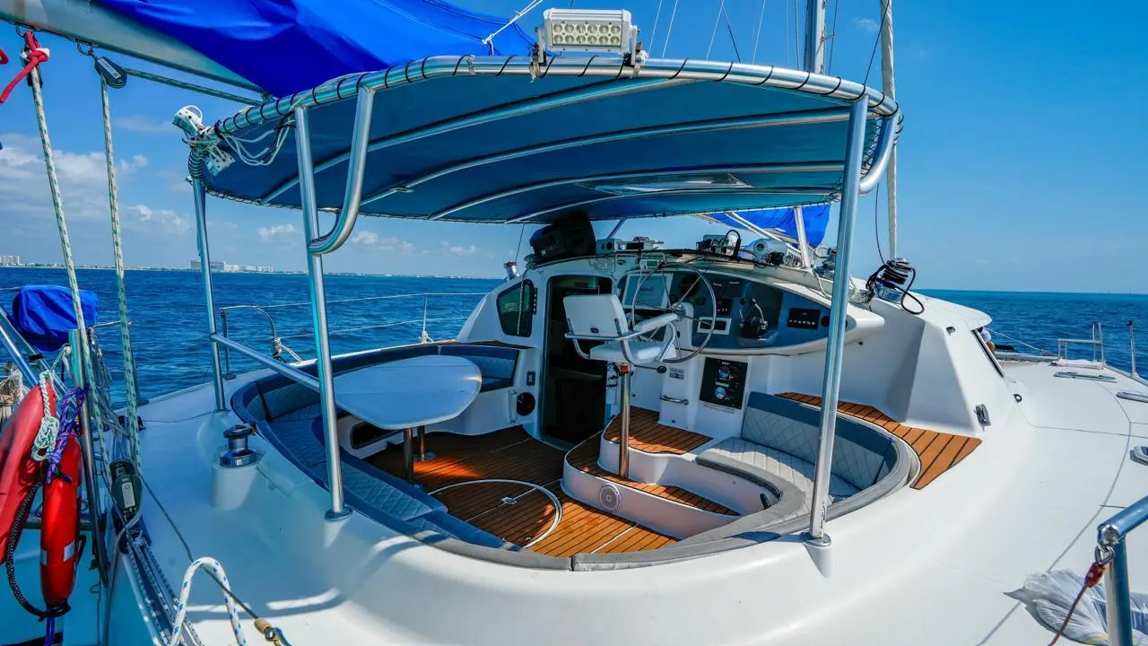 Shaded cockpit of a sailing catamaran with helm station and curved seating on the sea off Cancún