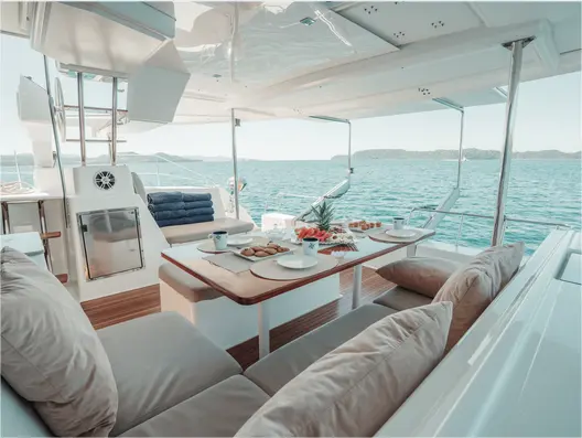 Shaded cockpit of a sailing catamaran with a laid table facing the Gulf of Papagayo