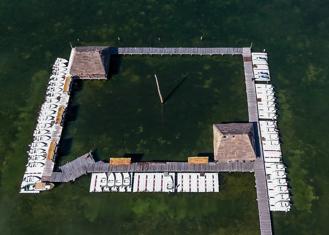 Aerial view of a square dock with thatched huts and rows of small speedboats on Nichupté Lagoon