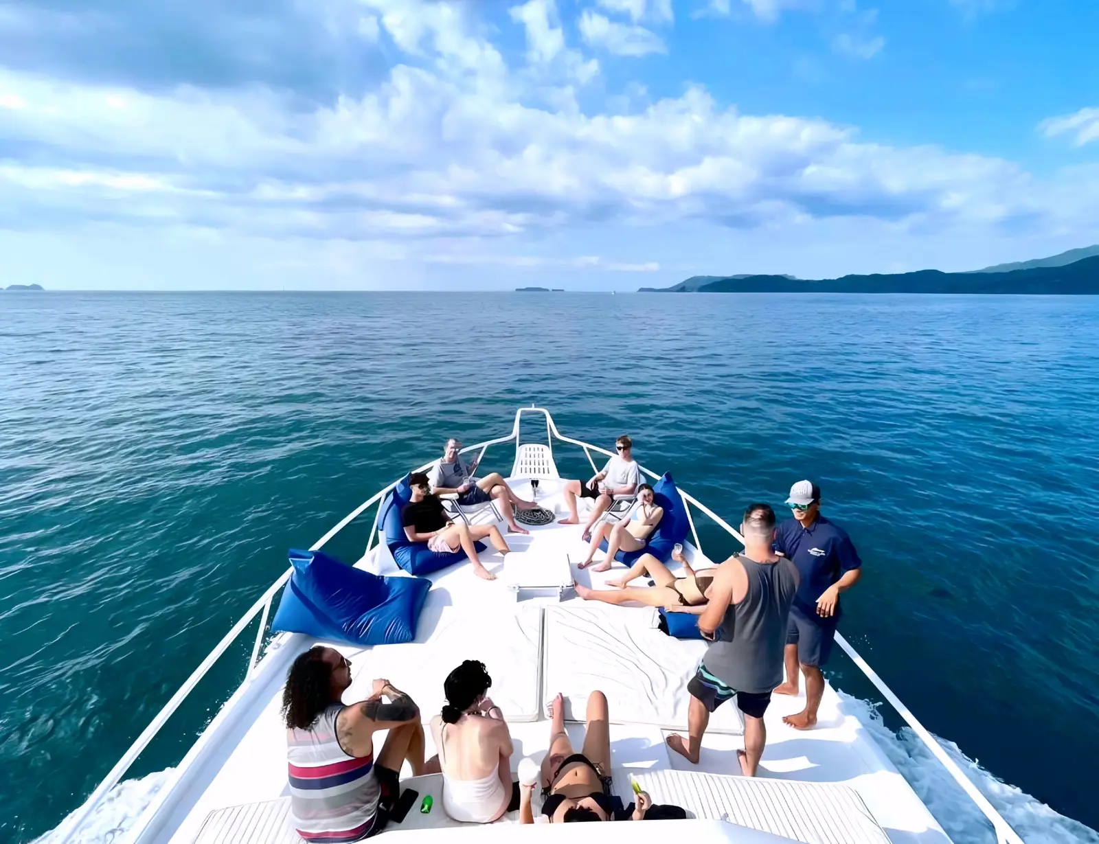 Guests relax on blue bean bags on the bow of a sportfishing yacht cruising calm water off Guanacaste