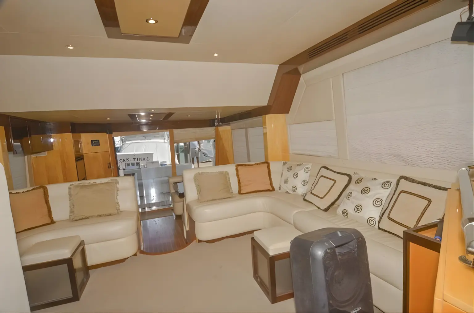 Yacht salon with cream sectional sofas, patterned cushions and wood paneling