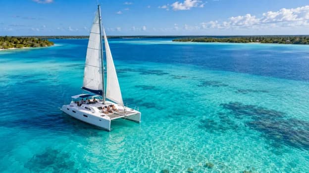Private catamaran sailing across the crystal clear turquoise waters of Bacalar Lagoon in Mexico with guests enjoying a scenic boat excursion.