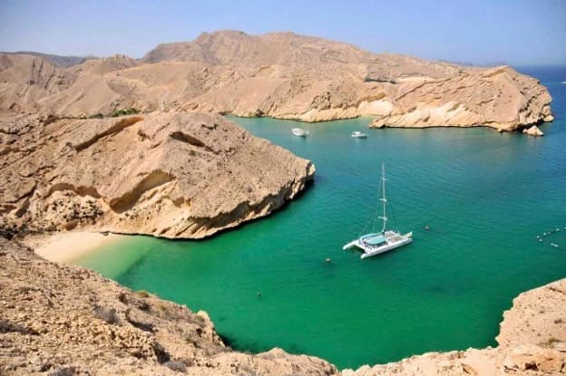 Best things to do in Oman in December, including relaxing on scenic beaches, exploring the coastline by boat, and enjoying views of rugged mountains and turquoise waters.