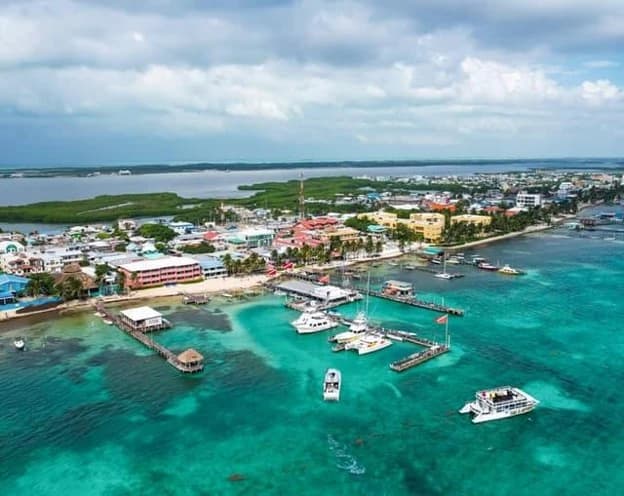 Aerial view of San Pedro, Ambergris Caye, Belize, showing catamarans and boats anchored in turquoise Caribbean waters near the waterfront and docks.