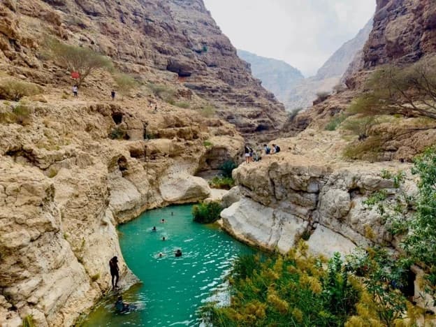 Outdoor experiences to enjoy in Oman in December, including coastal boat trips, snorkeling in clear turquoise waters, hiking through rugged mountains, and exploring scenic beaches.