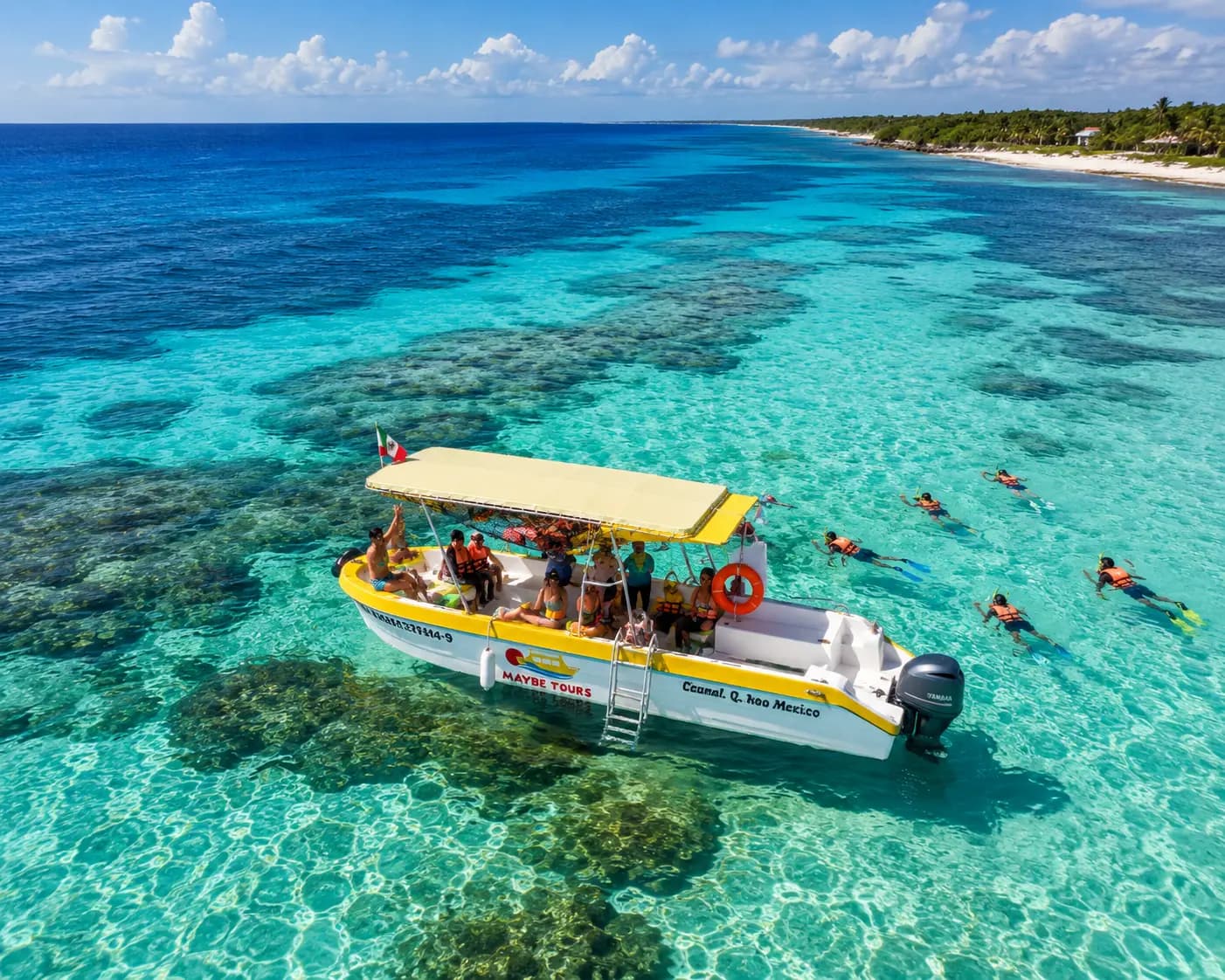 Aerial view of a canopied speedboat anchored over a turquoise reef off Cozumel as snorkelers swim nearby