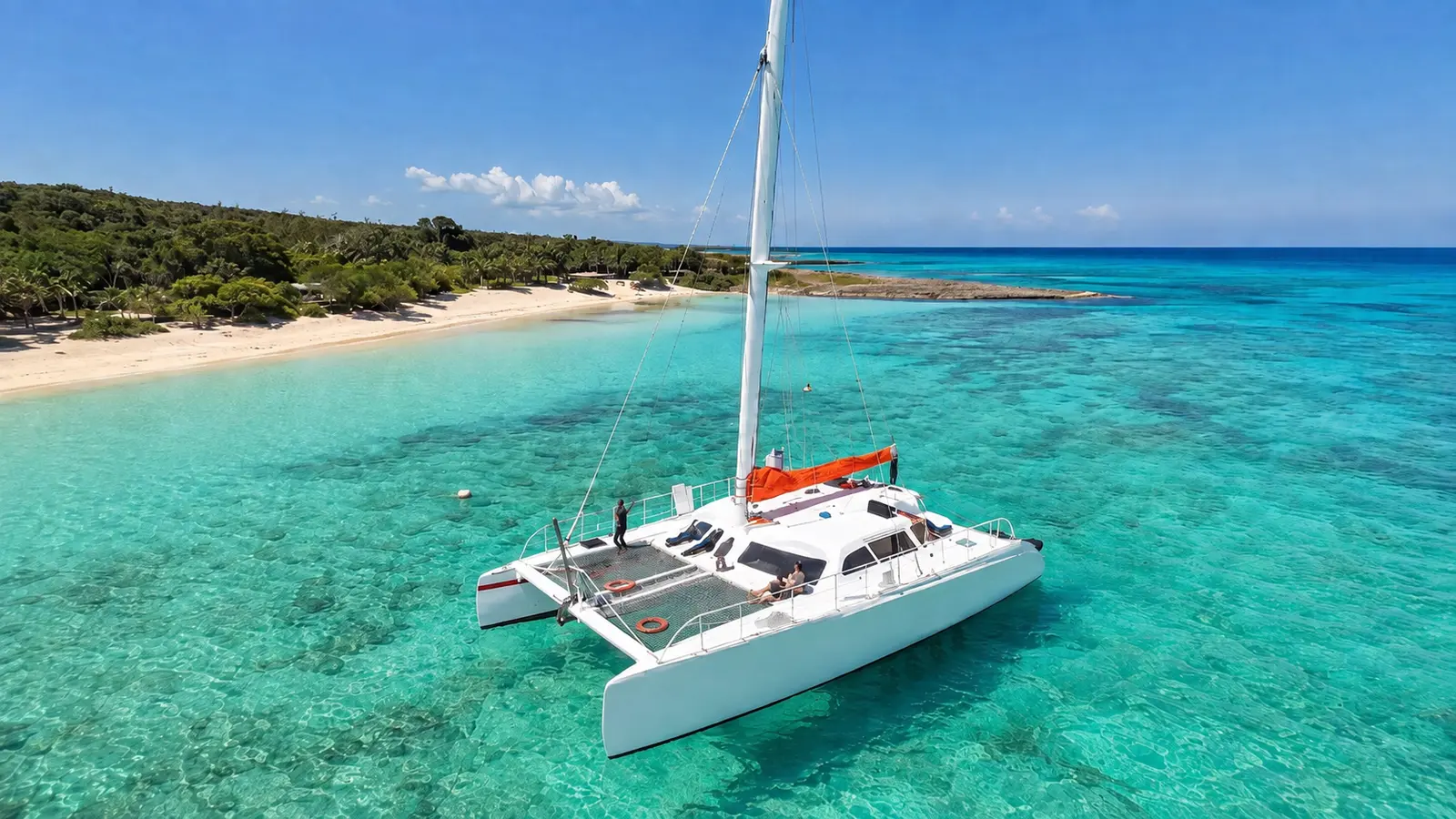 Sailing catamaran anchored in clear turquoise water off the white sand of Bahia de las Aguilas