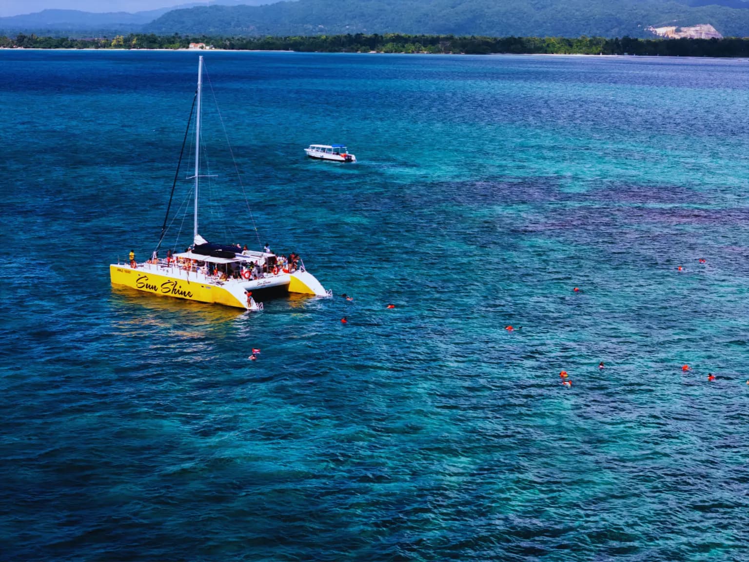 Yellow catamaran with swimmers in clear water off Negril, Jamaica