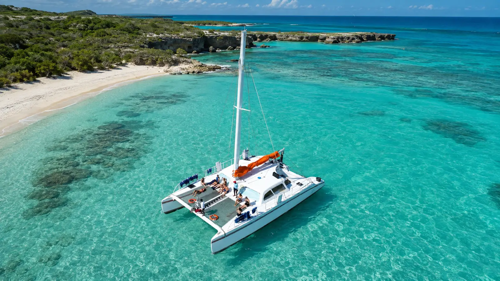 Aerial view of a sailing catamaran anchored over reef patches near the white sand of Bahia de las Aguilas