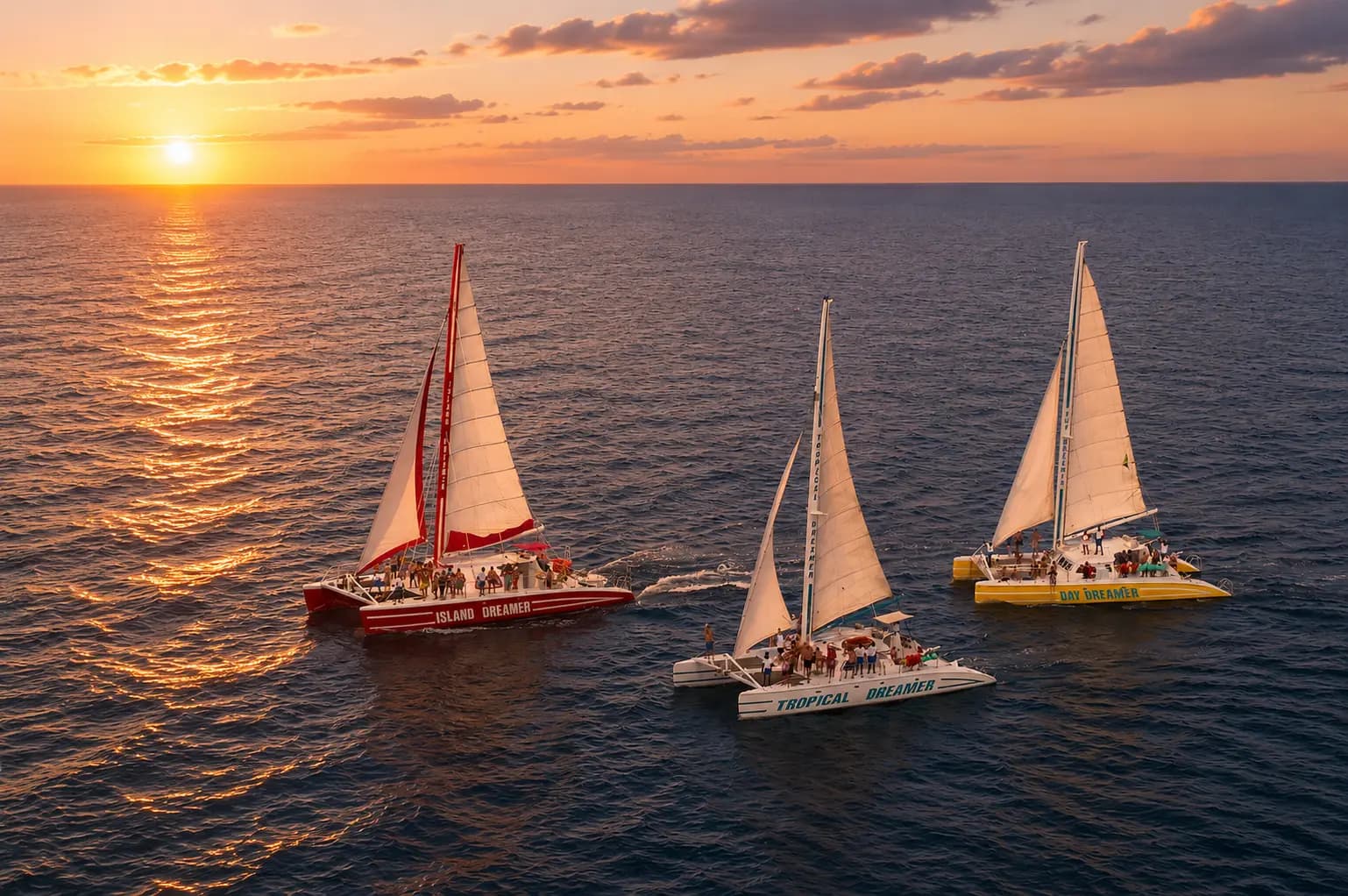Three sailing catamarans gliding across the sea off Montego Bay at sunset, seen from above