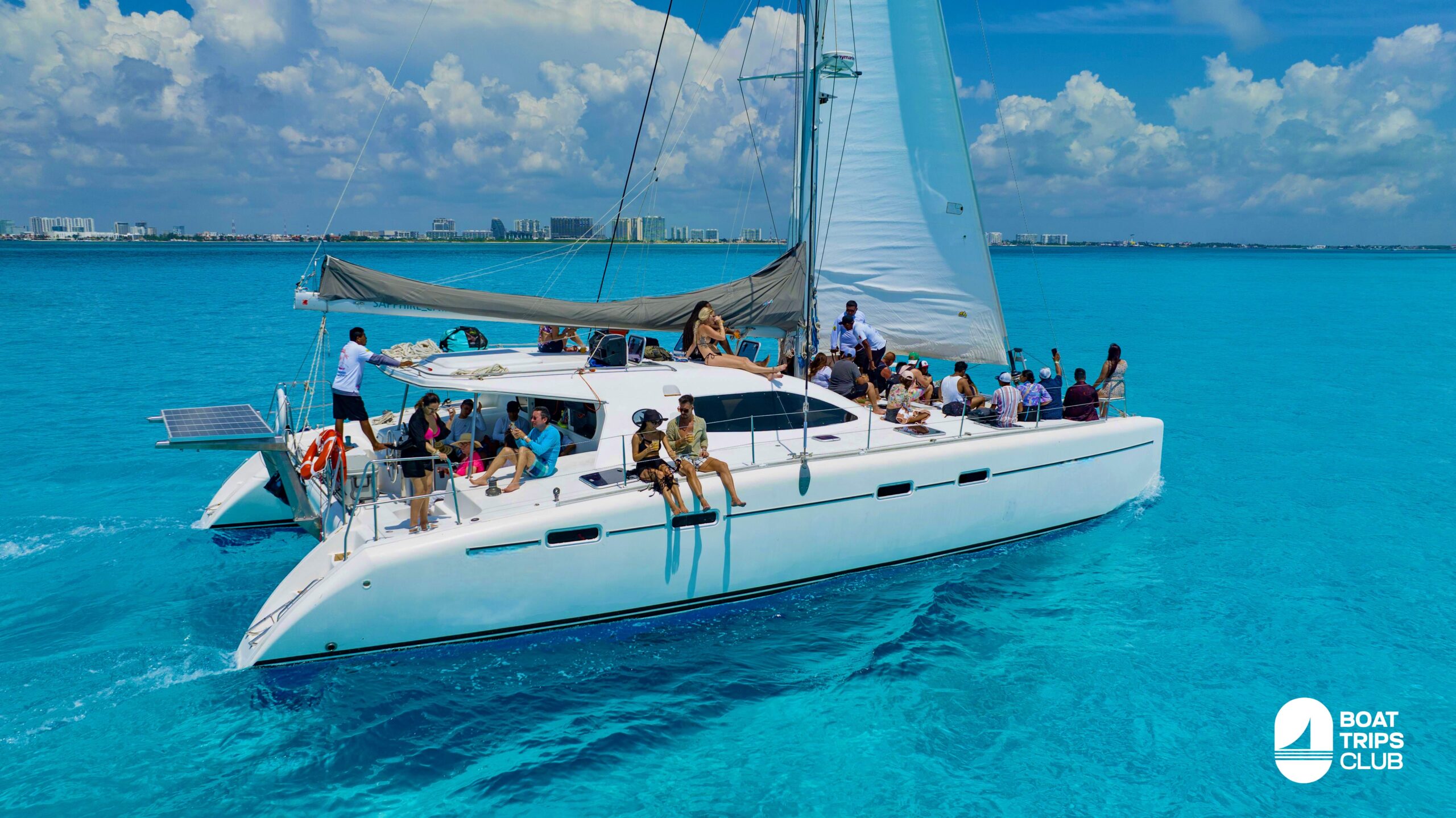 Tourists enjoying a catamaran ride in Cancun with crystal-clear turquoise waters, snorkeling among coral reefs and tropical fish, near Isla Mujeres.
