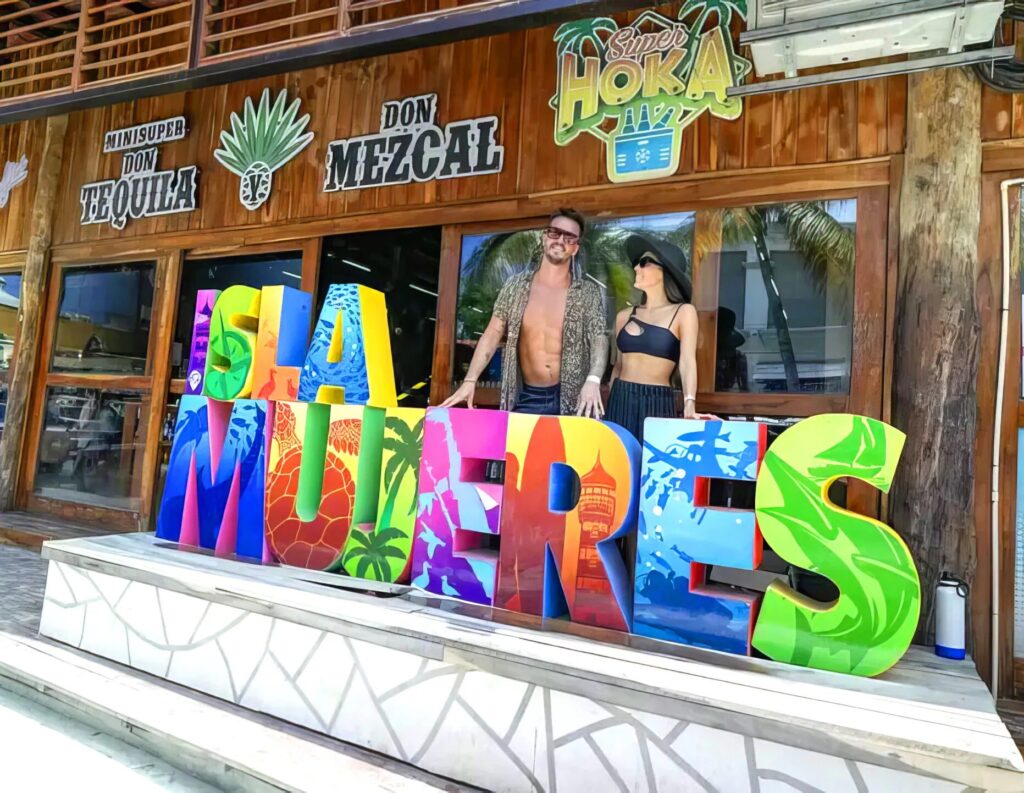 Couple taking pictures with isla mujeres sign board