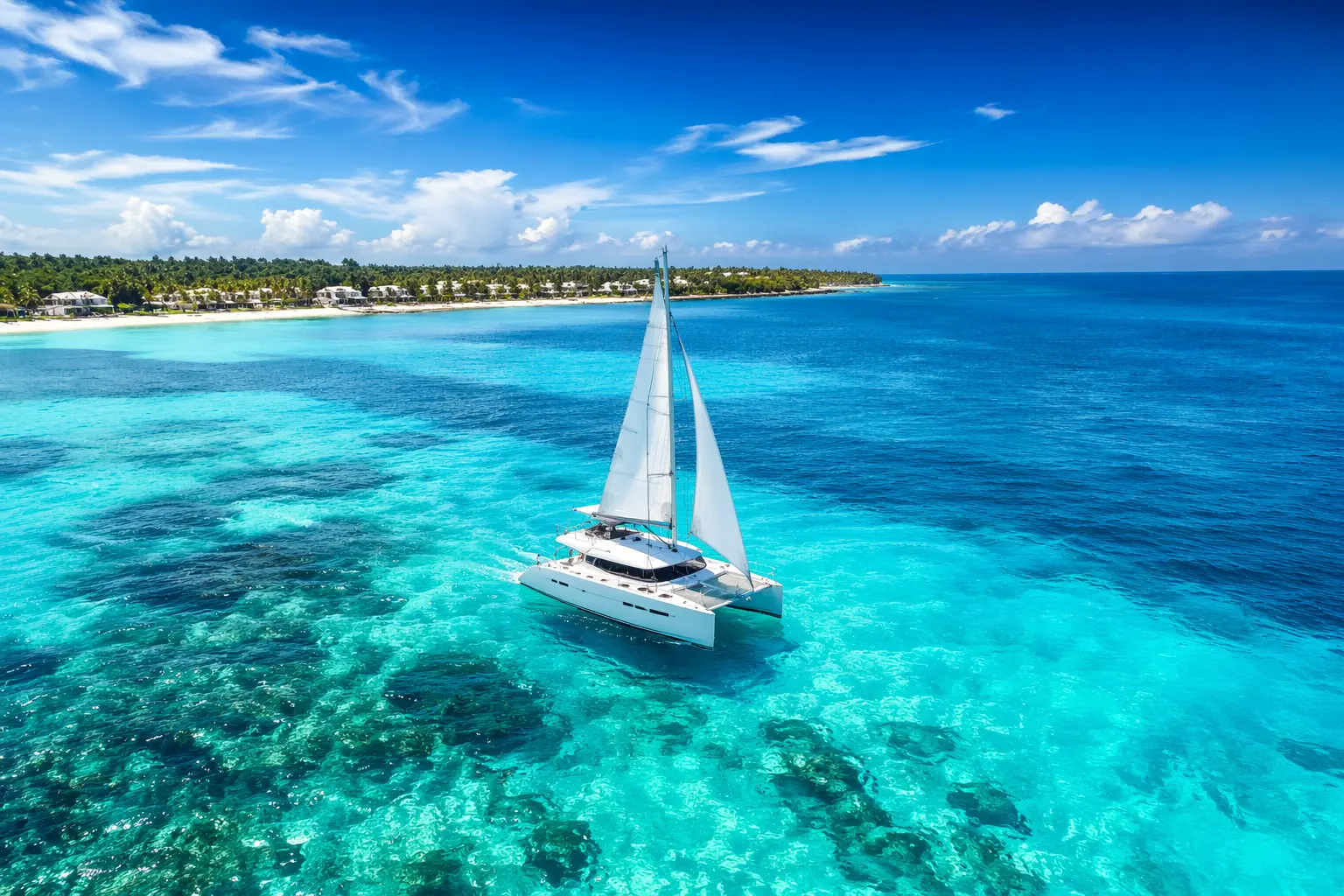 Best catamaran tours Cancun experience with a luxury white catamaran sailing on crystal-clear turquoise waters near Isla Mujeres coastline in high-definition landscape