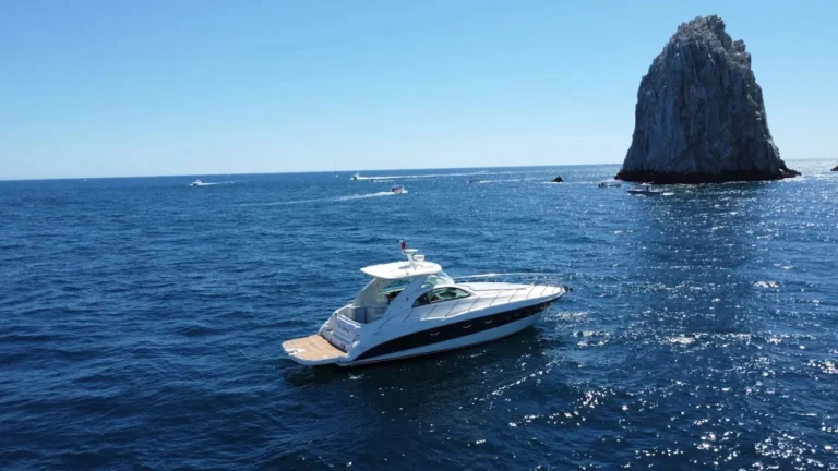 Best Time to Visit Cabo San Lucas featuring a luxury yacht cruising through deep blue ocean waters near a dramatic rocky sea formation.