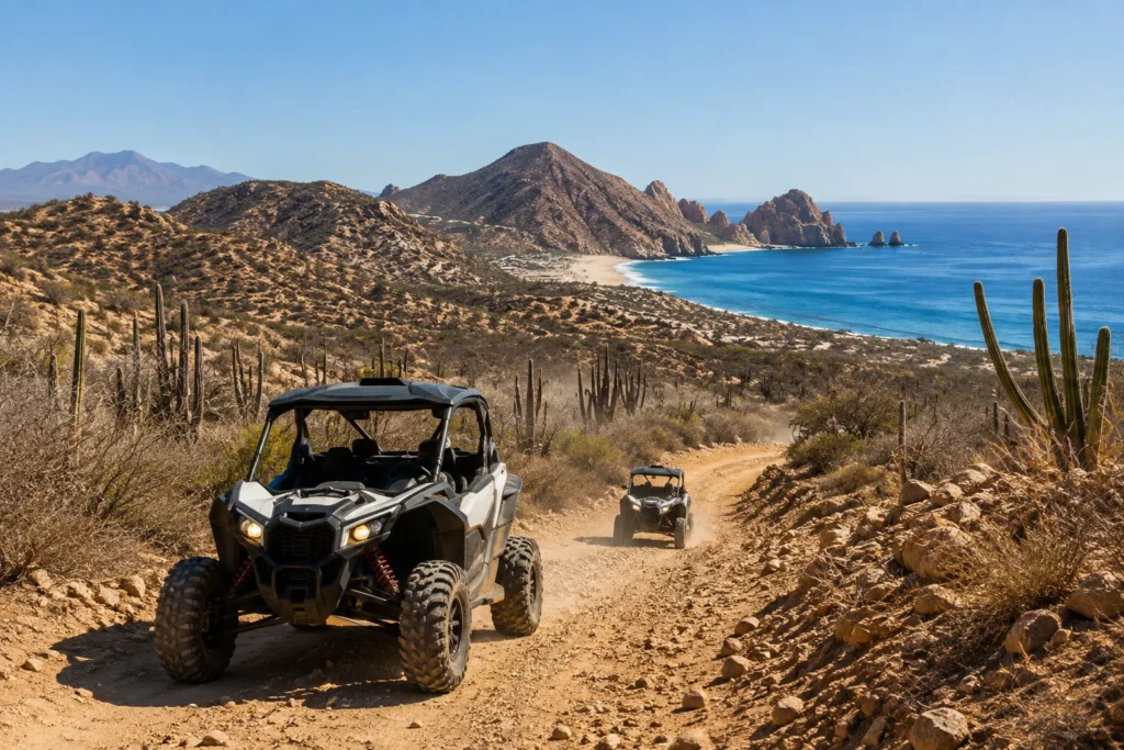 Off-road UTVs driving along a rugged Baja desert trail overlooking the coastline and turquoise waters of Los Cabos.