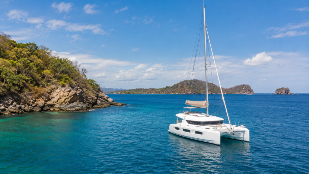 White catamaran anchored in calm blue Pacific waters near the Guanacaste coastline, representing catamaran tours from Flamingo Marina in Playa Flamingo.