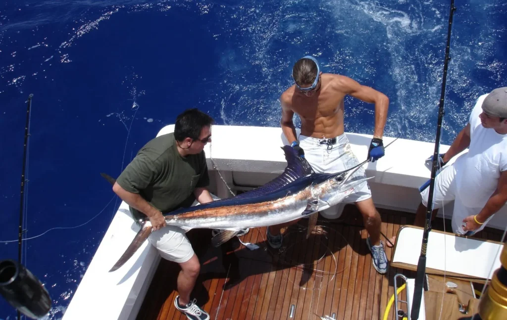 Deep-sea fishing in Puerto Plata featuring a sportfishing crew holding a sailfish aboard a private fishing charter boat.