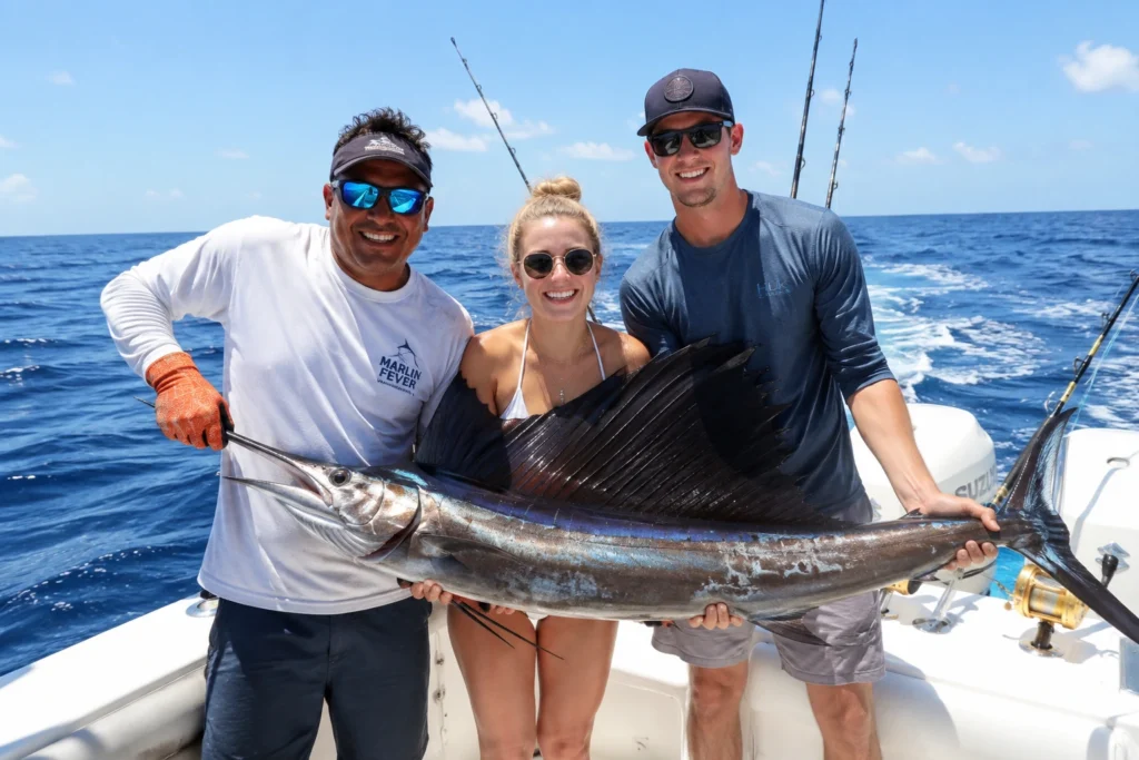 Happy guests on a sportfishing boat holding a large catch in clear blue Caribbean waters.