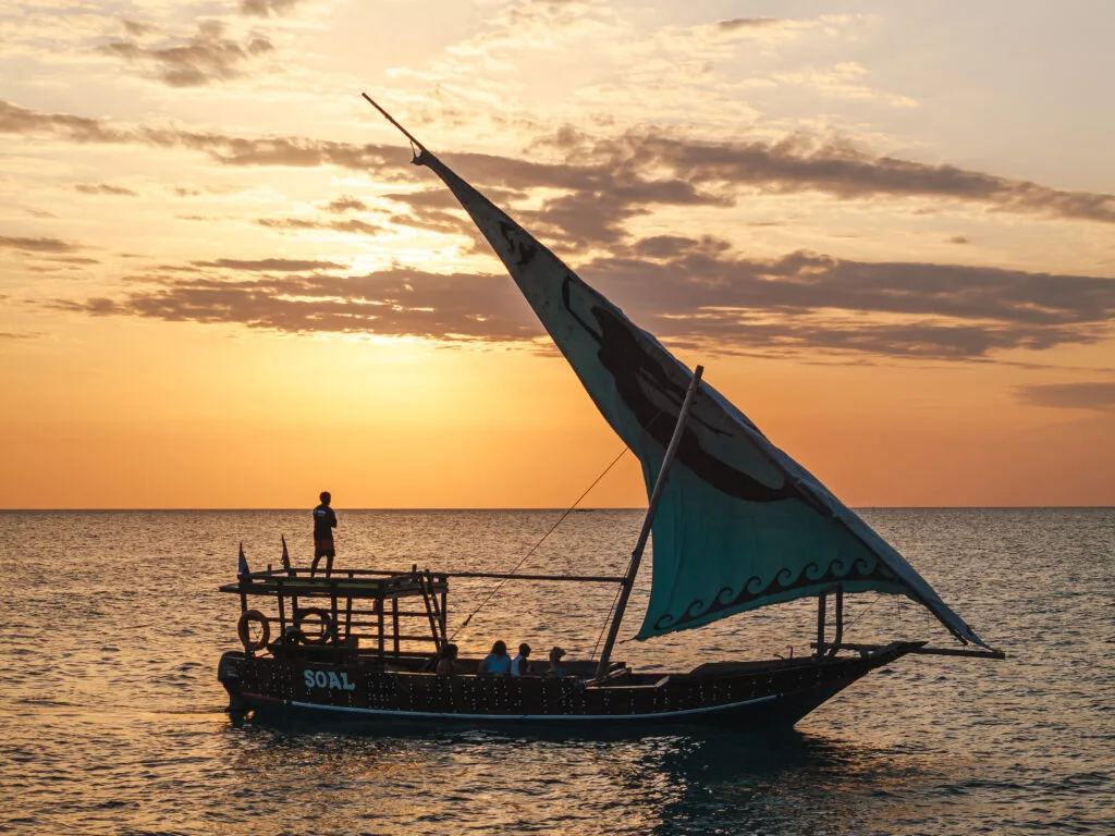 Sunset dhow cruise off Kendwa Beach in Zanzibar with a traditional wooden sailboat sailing across the Indian Ocean during a golden sunset.