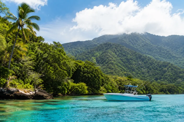 Costa Rica Fun Facts illustrated by a tropical rainforest coastline with crystal-clear turquoise water, lush green mountains, and a boat anchored in a peaceful bay.