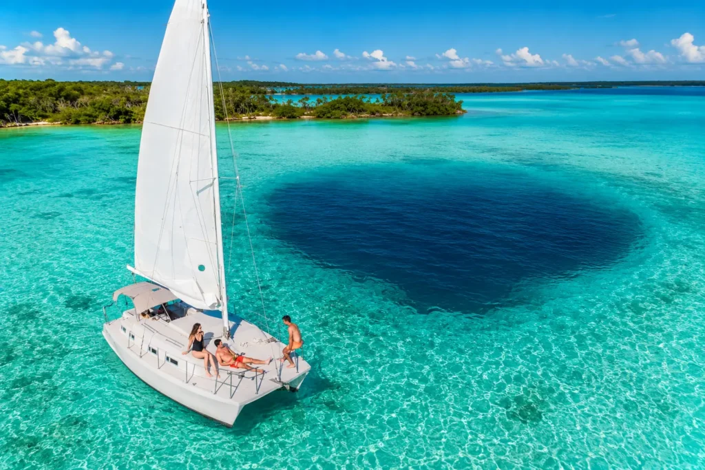 Private catamaran sailing on Bacalar Lagoon, one of the best things to do in Bacalar, with crystal-clear turquoise water and the famous Cenote Negro below.