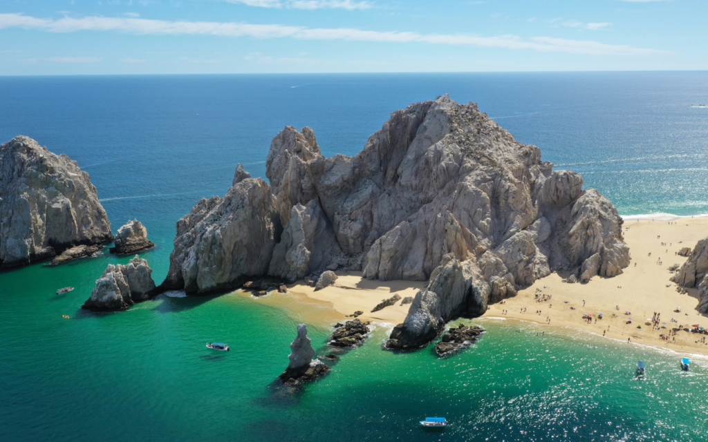 Aerial view of a secluded beach with turquoise water and dramatic rock formations near Cabo San Lucas, Mexico.