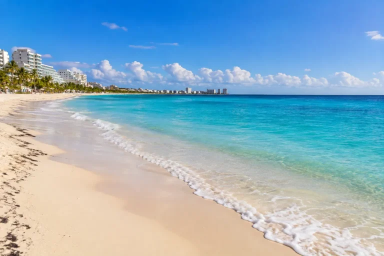 Cancun Travel Advisory featuring a quiet Cancun beach with turquoise water, white sand, and the Hotel Zone under a clear blue sky.