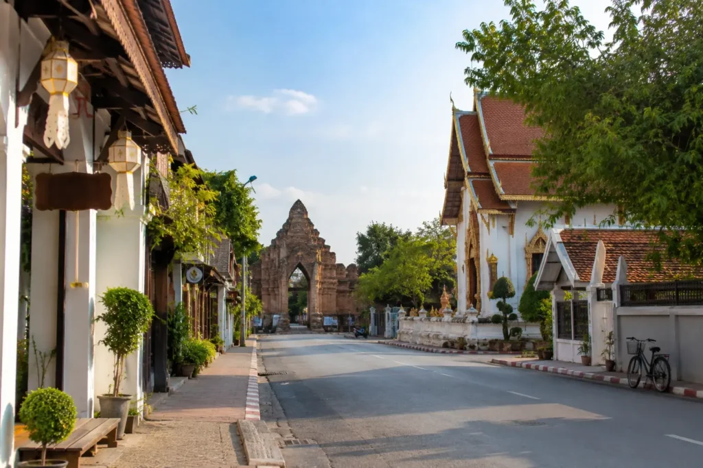 Historic temple street in Chiang Mai, Thailand, featuring traditional Thai architecture and a historic gate.