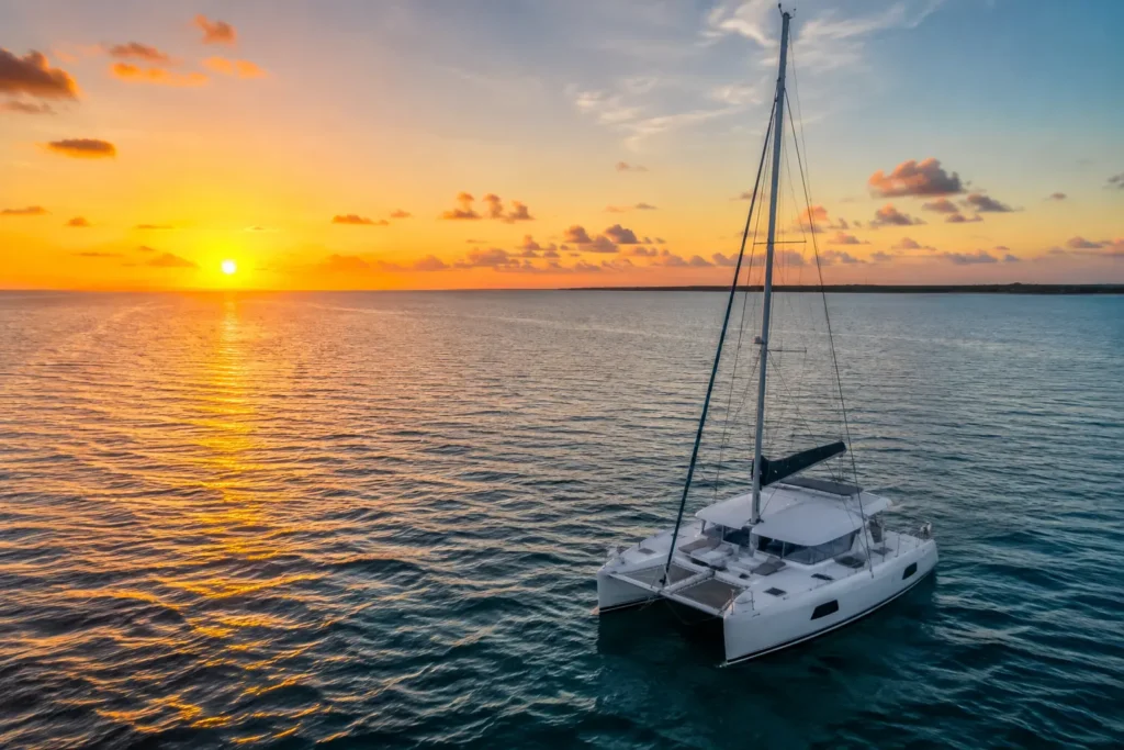 Best time for boat and catamaran tours in Cozumel with a luxury catamaran sailing on deep blue water during a golden sunset.